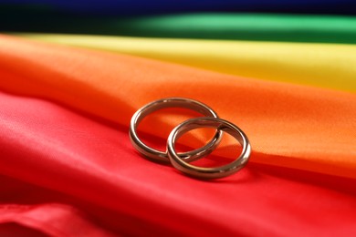 Wedding rings on rainbow LGBT flag, closeup