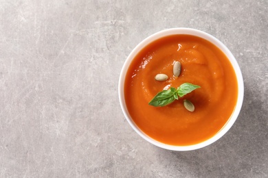 Photo of Bowl of tasty sweet potato soup on grey background, top view. Space for text