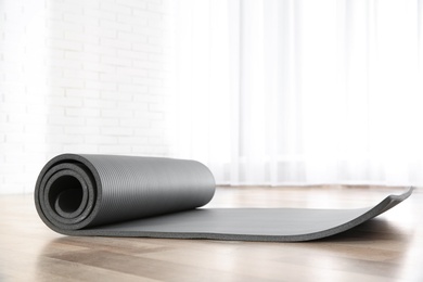 Photo of Rolled grey yoga mat on floor indoors