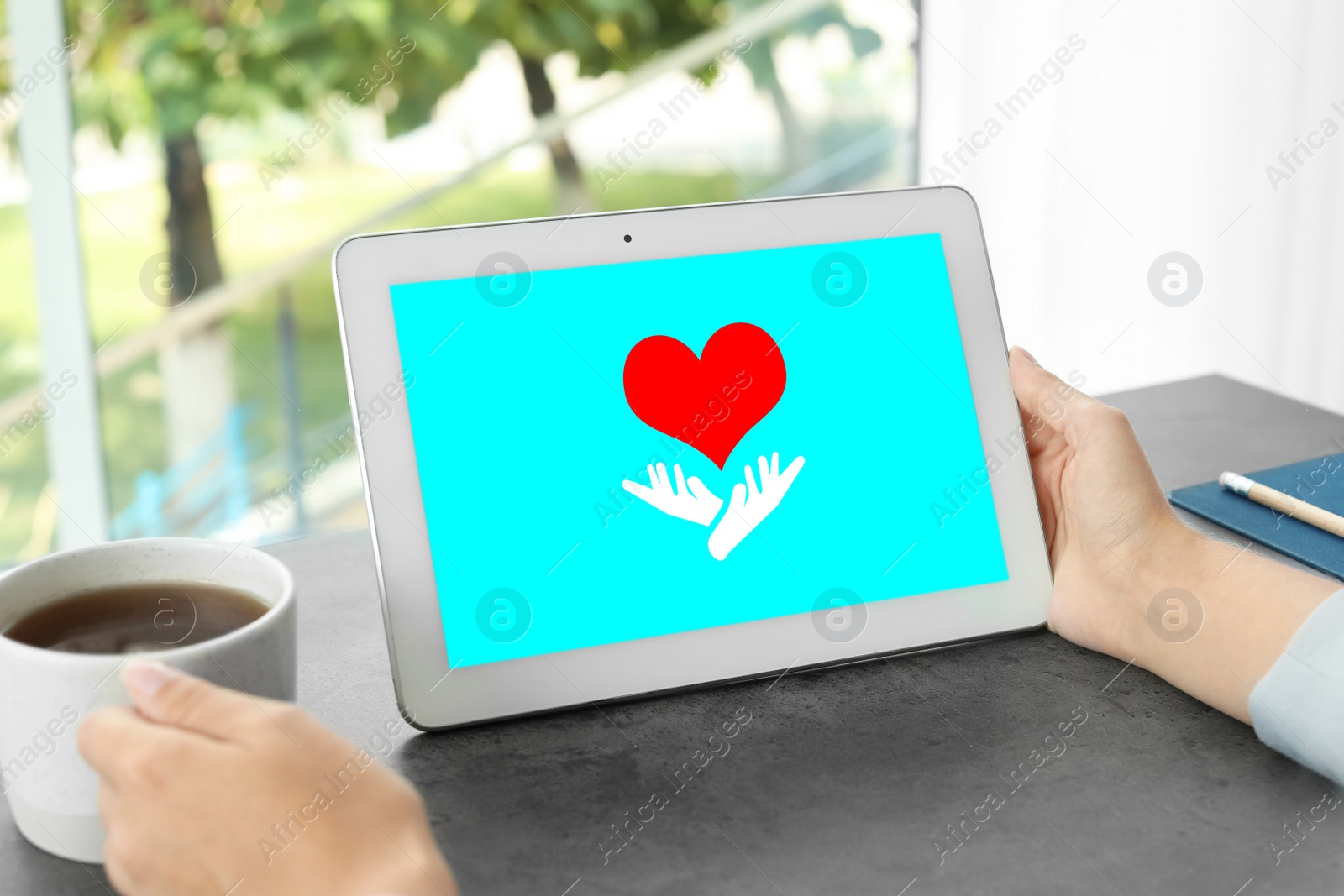 Image of Donations concept. Woman with tablet and cup of coffee at table, closeup