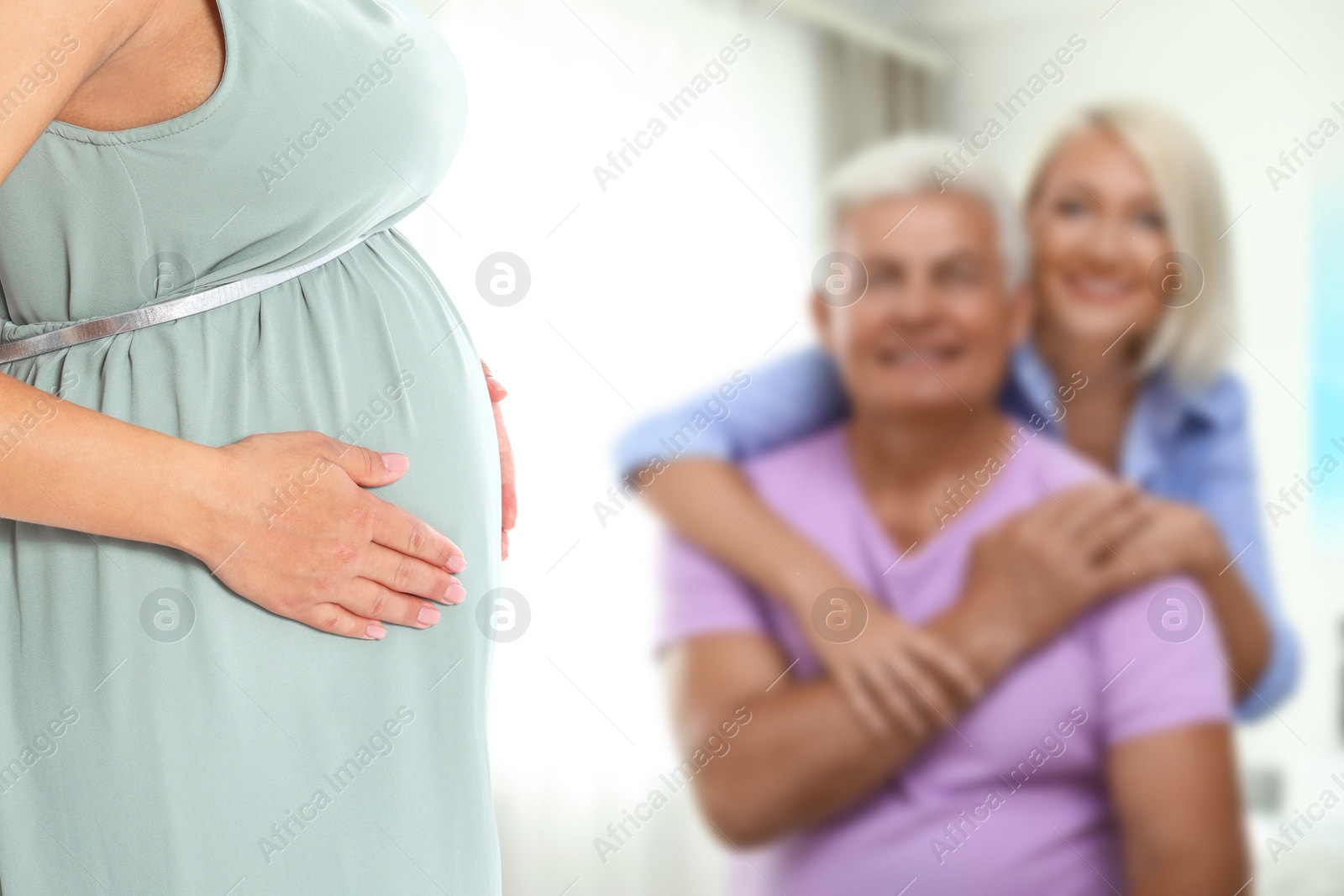 Image of Surrogacy concept. Young pregnant woman and blurred view of happy mature couple indoors