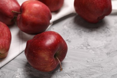 Photo of Fresh red apples on grey textured table, closeup. Space for text