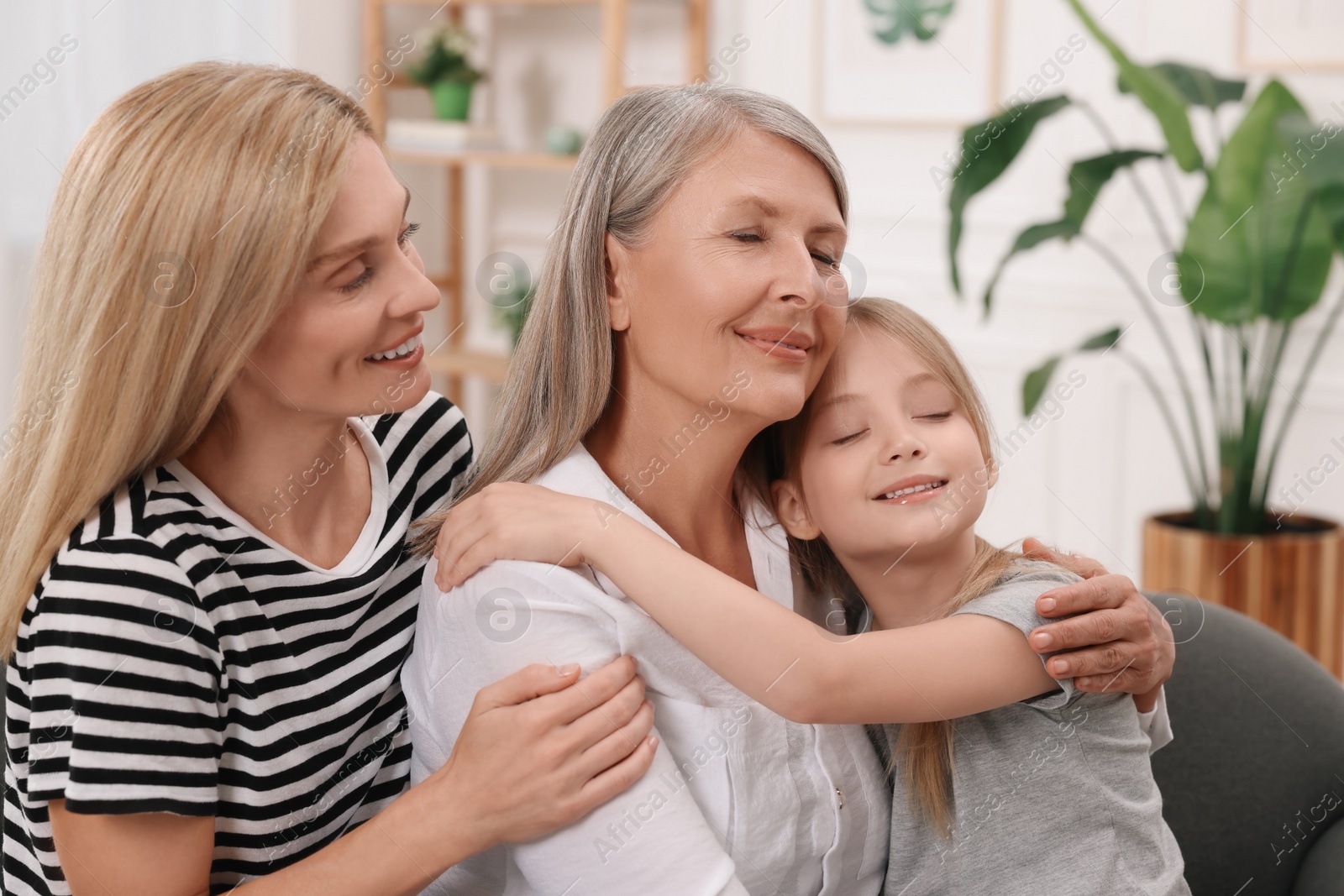 Photo of Three generations. Happy grandmother, her daughter and granddaughter at home