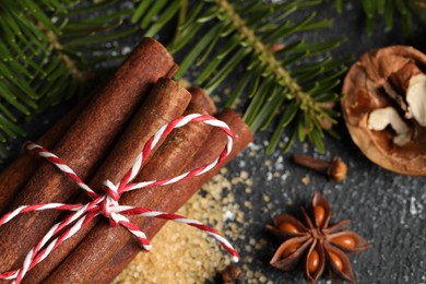 Different aromatic spices and fir branches on grey table, flat lay