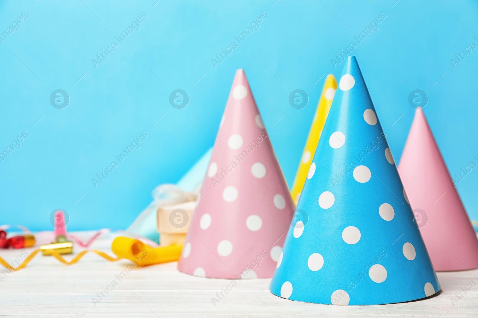 Photo of Birthday party caps on table against color background