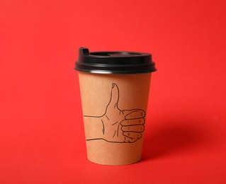 Takeaway paper cup with thumbs up gesture drawing on red background