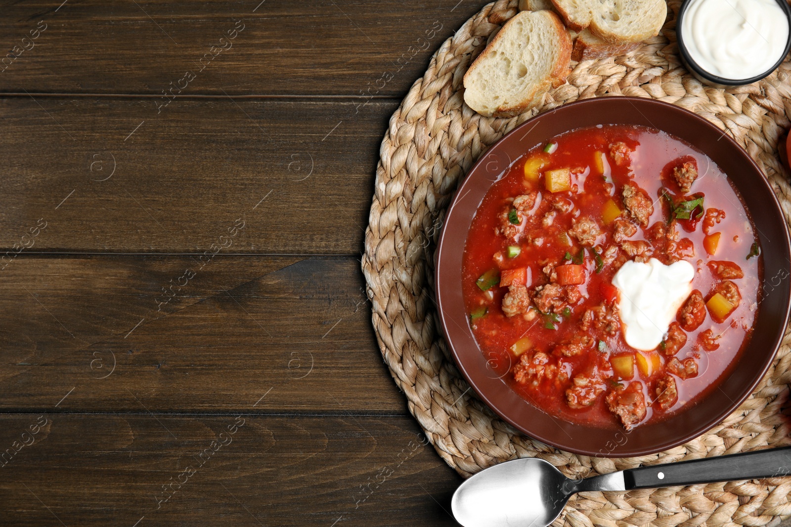 Photo of Bowl of delicious stuffed pepper soup served on wooden table, flat lay. Space for text