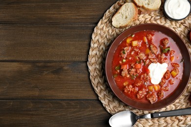 Bowl of delicious stuffed pepper soup served on wooden table, flat lay. Space for text