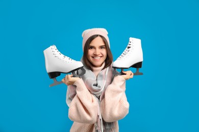 Photo of Happy woman with ice skates on light blue background
