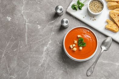 Bowl of fresh homemade tomato soup and space for text on grey table, top view