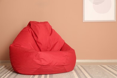 Photo of Red bean bag chair on floor near beige wall indoors