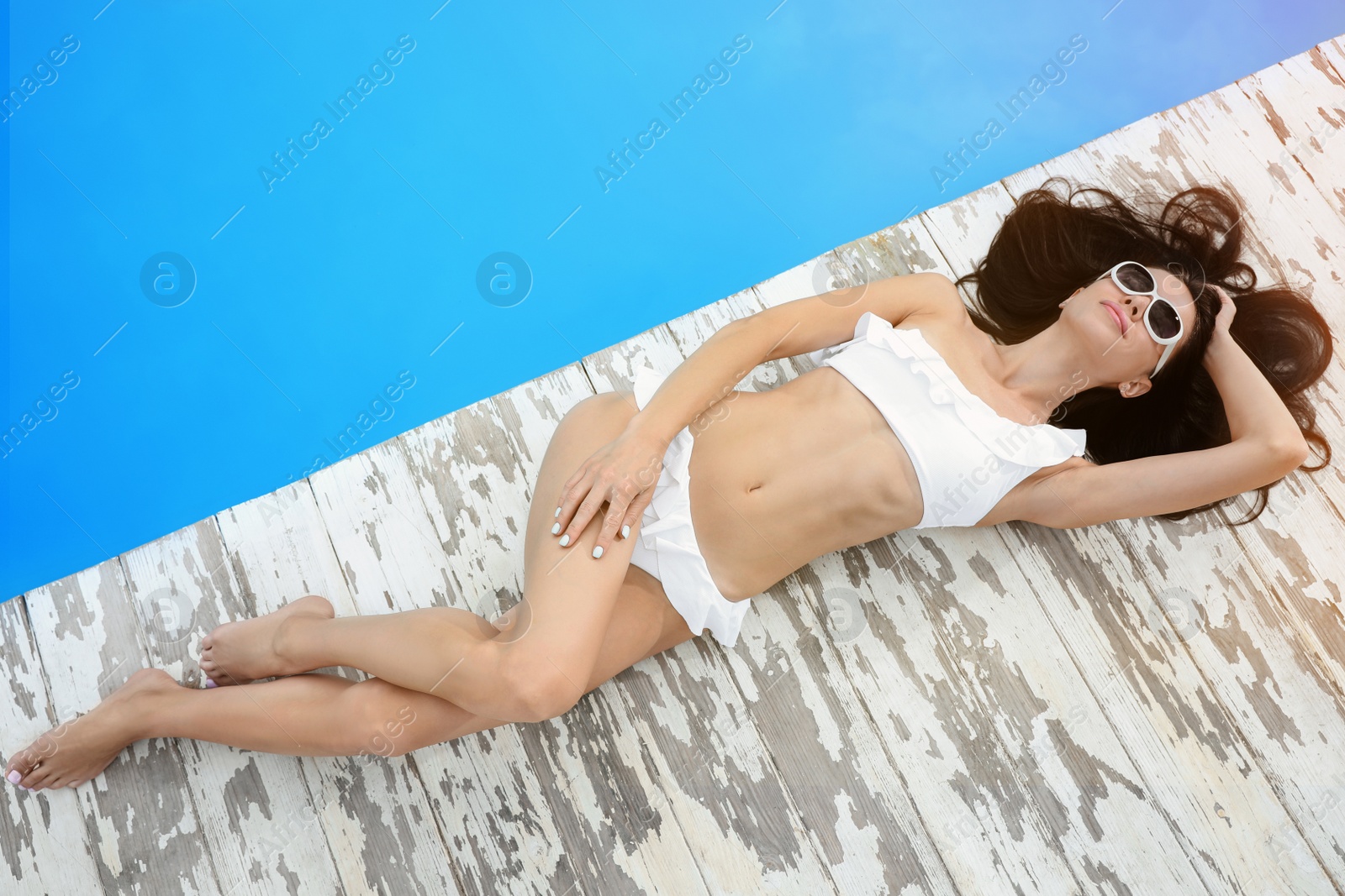 Photo of Young woman in stylish white bikini near swimming pool, above view