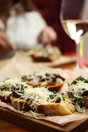 Delicious bruschettas with beef and cheese on wooden table, closeup