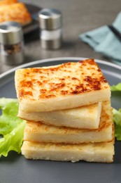 Photo of Delicious turnip cake with lettuce salad on grey plate, closeup