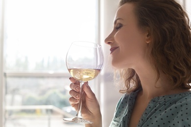 Woman with glass of delicious wine indoors