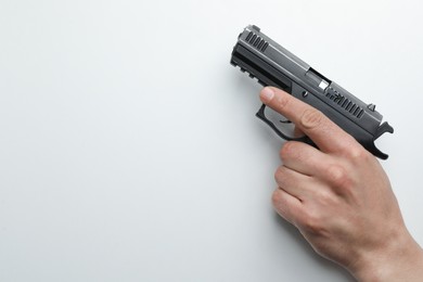 Photo of Man holding semi-automatic pistol on white background, closeup. Space for text