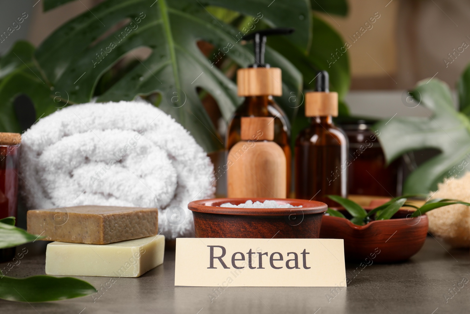 Photo of Card with word Retreat and different spa products on grey table