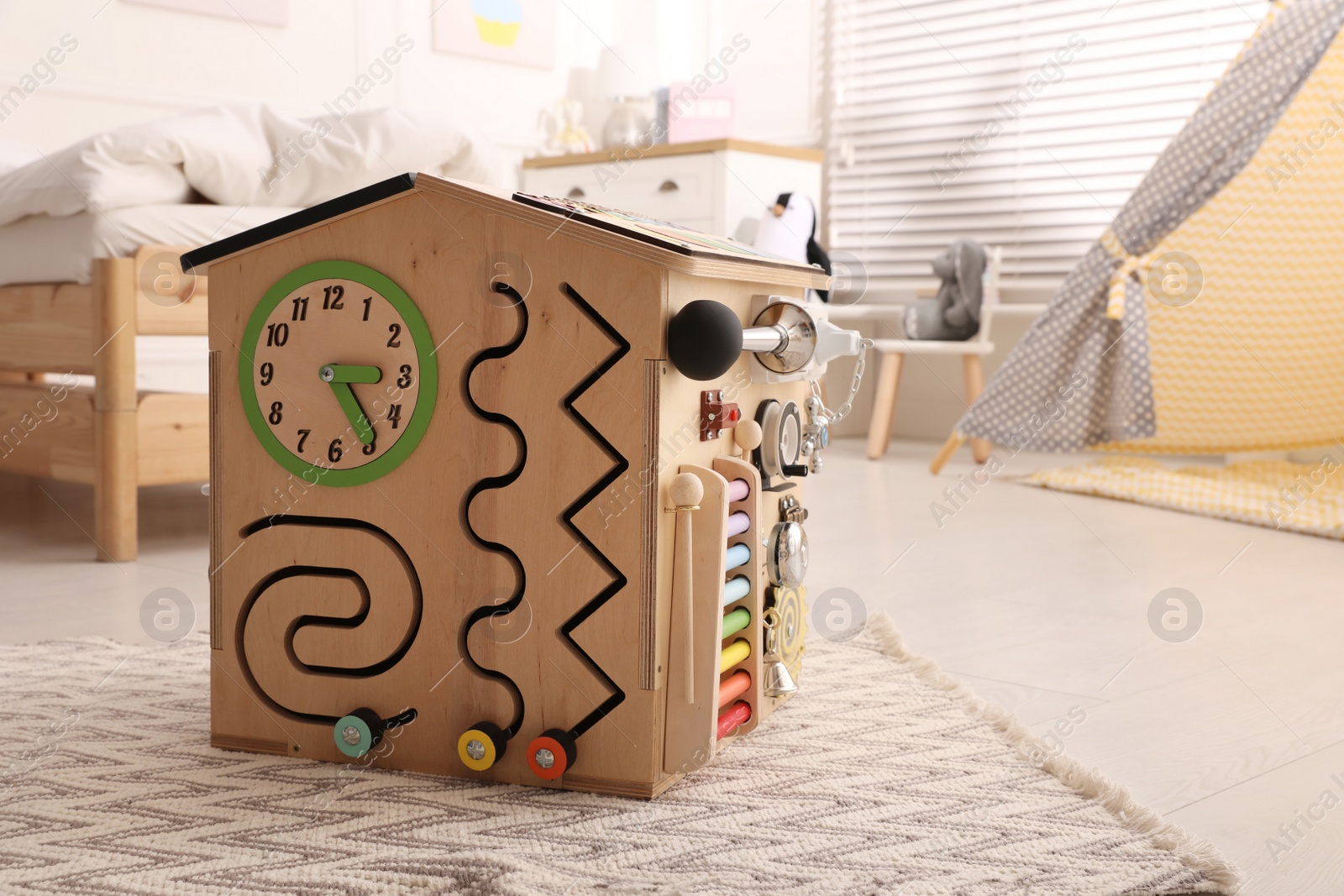 Photo of Busy board house on floor indoors, space for text. Baby sensory toy