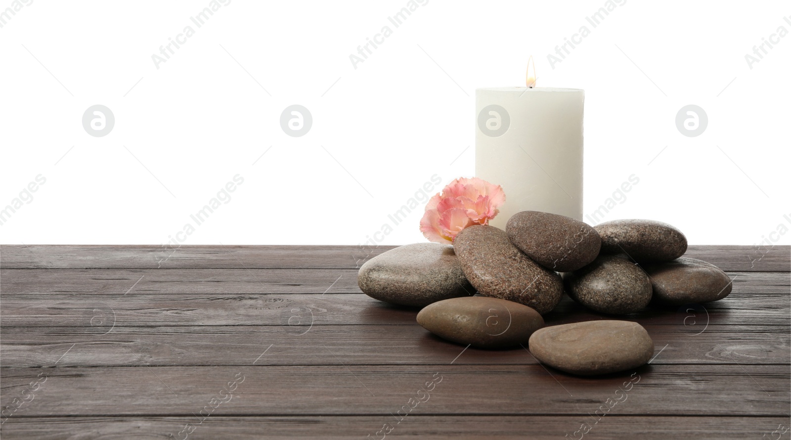 Photo of Spa stones, flower and candle on wooden table against white background. Space for text