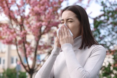 Photo of Woman with napkin suffering from seasonal allergy on spring day