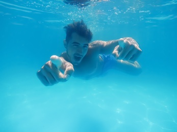 Photo of Handsome young man swimming in pool, underwater view