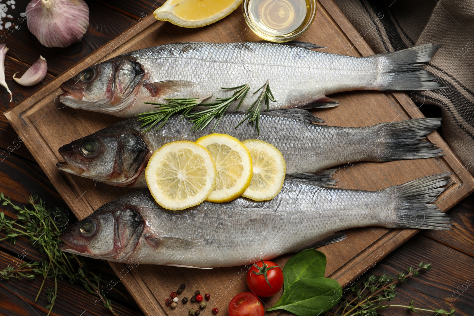 Photo of Sea bass fish and ingredients on wooden table, flat lay