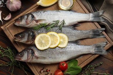 Sea bass fish and ingredients on wooden table, flat lay