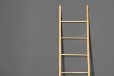 Modern wooden ladder on grey background. Space for text