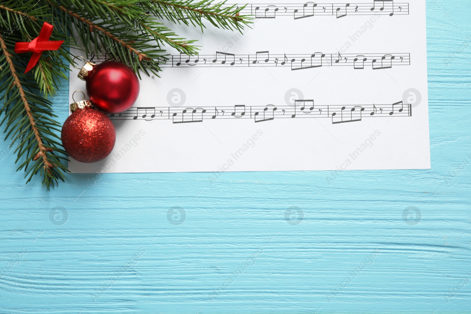 Photo of Flat lay composition with Christmas decorations and music sheet on blue wooden table, space for text