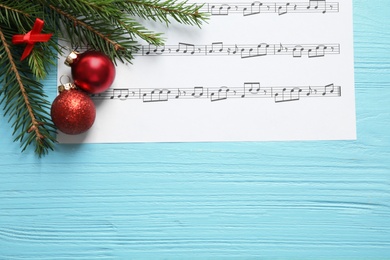 Flat lay composition with Christmas decorations and music sheet on blue wooden table, space for text