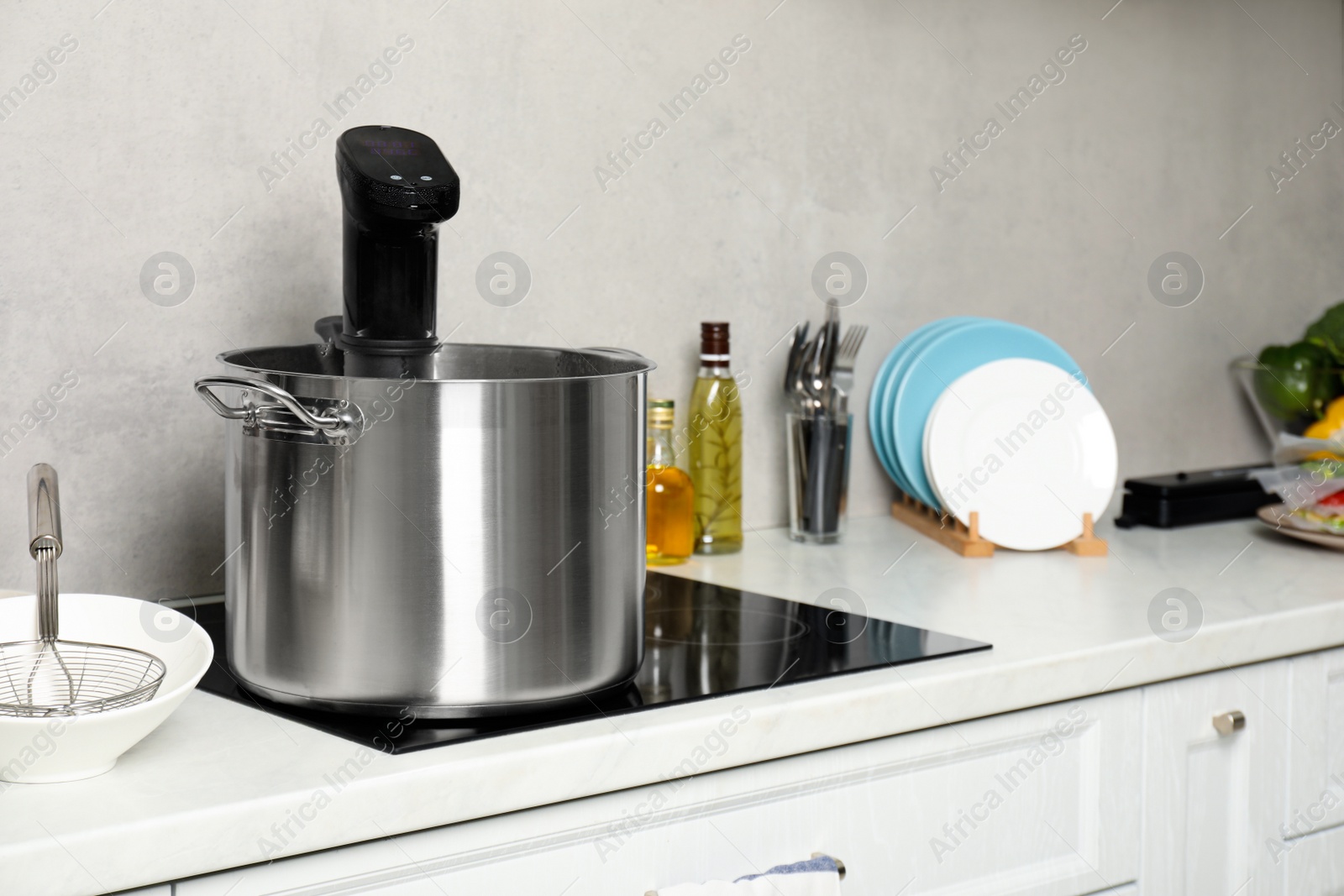 Photo of Pot with sous vide cooker in kitchen. Thermal immersion circulator