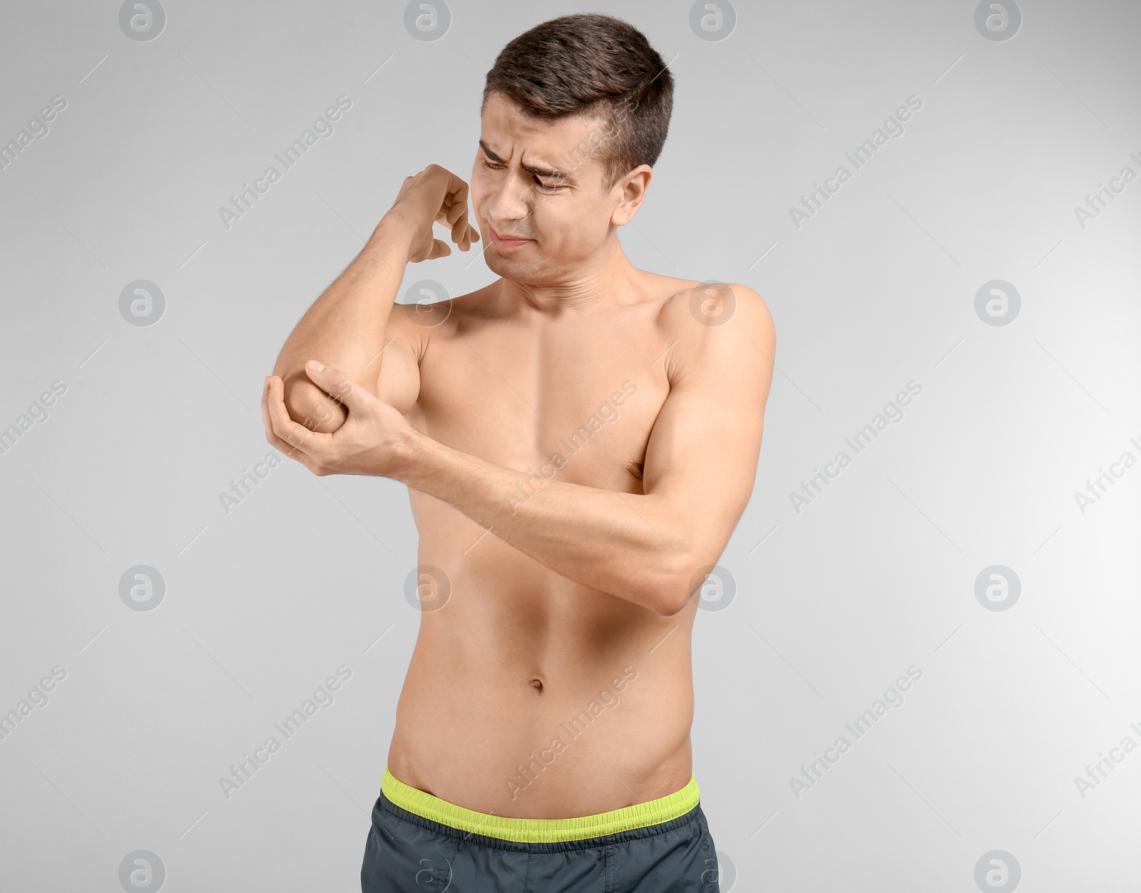 Photo of Young man suffering from pain in elbow on light background