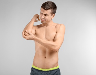 Photo of Young man suffering from pain in elbow on light background