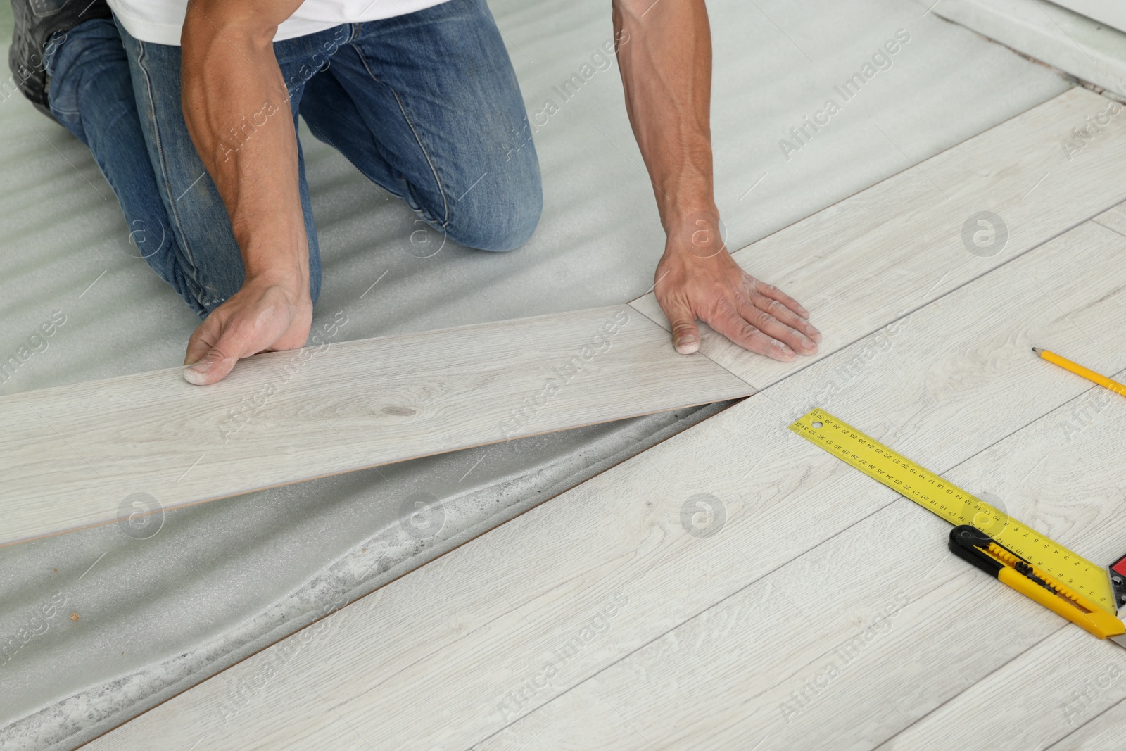 Photo of Man installing new laminate flooring indoors, closeup