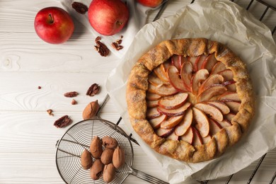 Delicious apple galette and pecans on white wooden table, flat lay