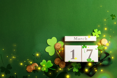 Flat lay composition with wooden block calendar on green background, space for text. St. Patrick's Day celebration