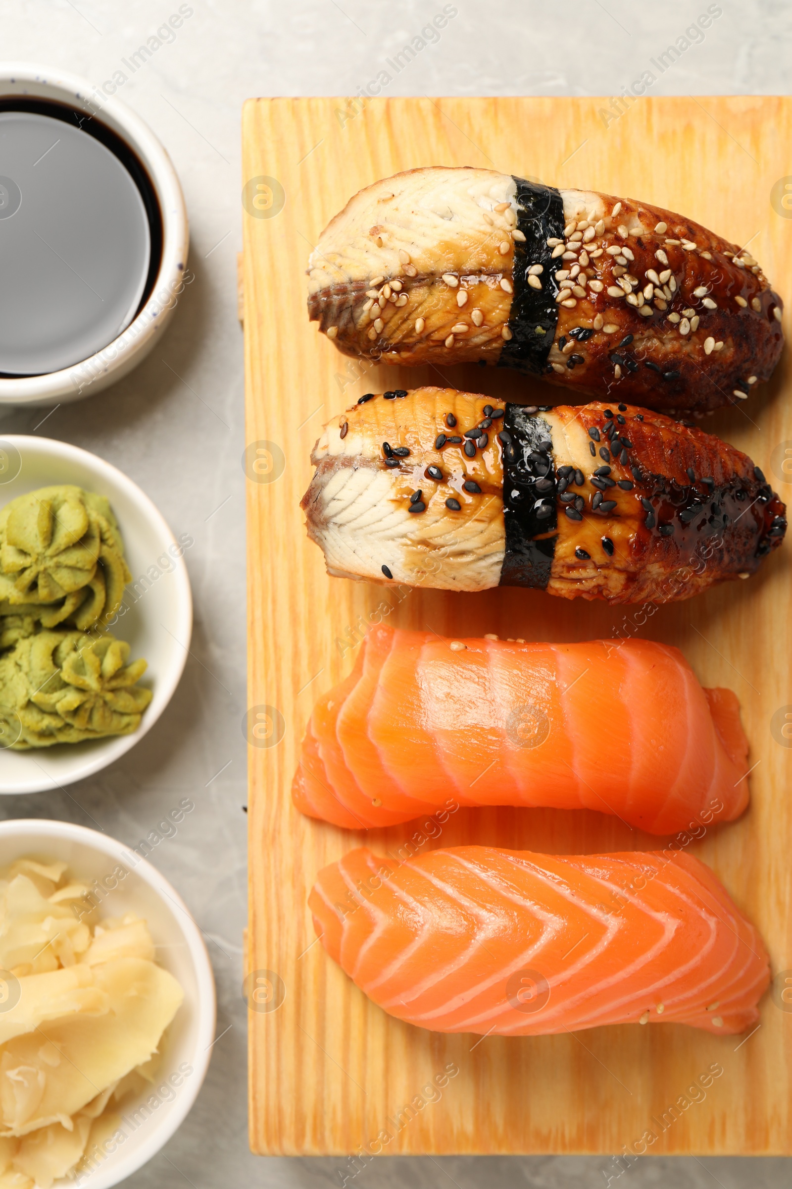 Photo of Delicious nigiri sushi, soy sauce, wasabi and ginger on light table, flat lay