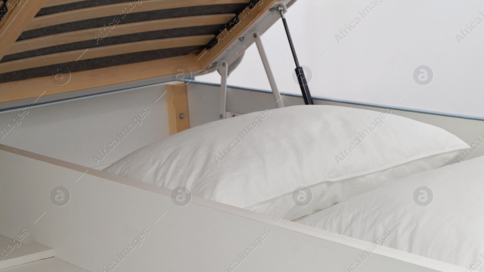 Photo of Storage drawer under bed with white pillows indoors, closeup