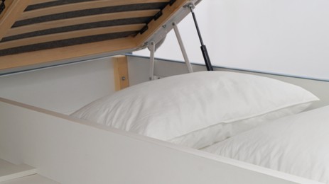 Photo of Storage drawer under bed with white pillows indoors, closeup