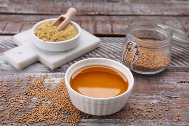 Photo of Bowl of natural oil, mustard seeds and powder on wooden table