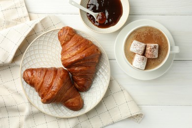 Flat lay composition with tasty croissants and cup of hot drink on white wooden table