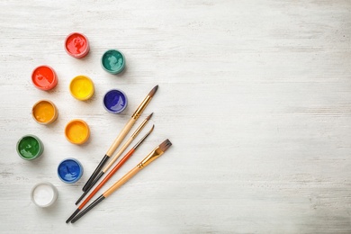 Photo of Flat lay composition with different paints and brushes on wooden background. Color palette