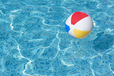 Photo of Inflatable beach ball floating in swimming pool, space for text