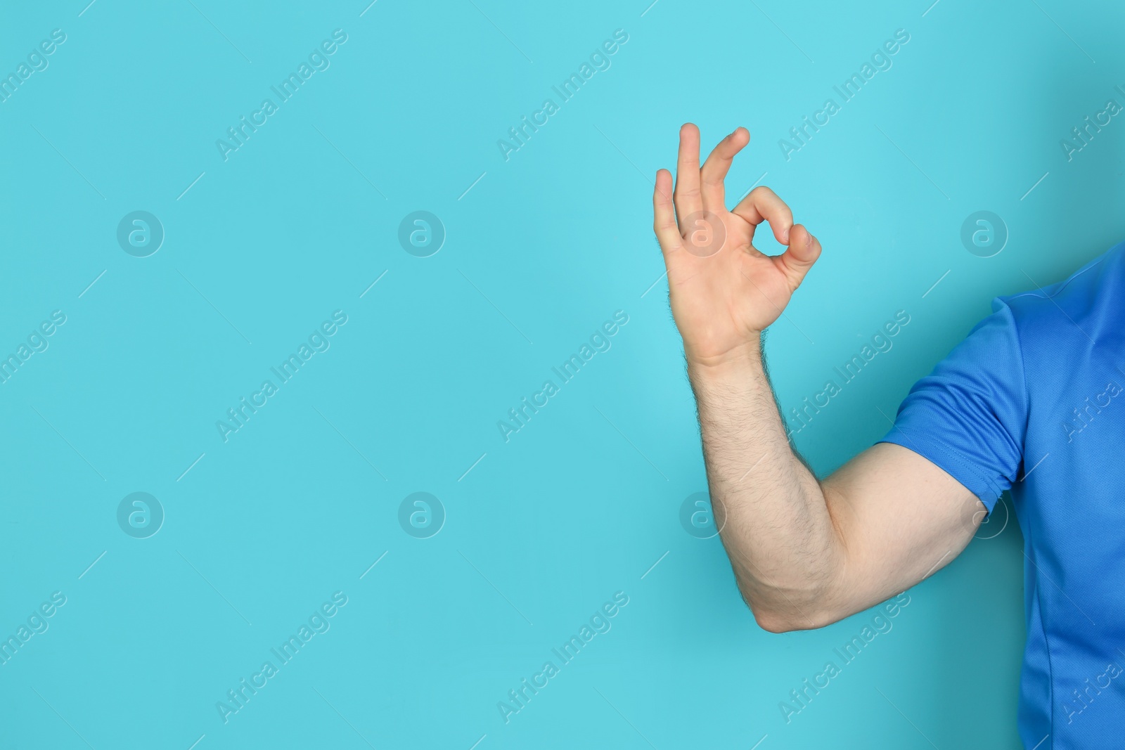 Photo of Young man showing OK gesture on color background. Space for text