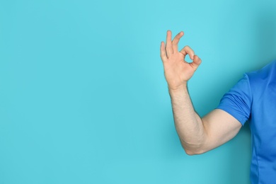 Photo of Young man showing OK gesture on color background. Space for text