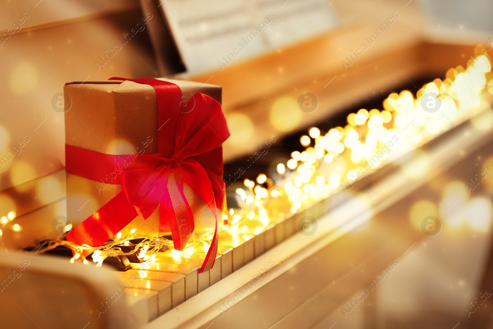 Image of Gift box and fairy lights on piano. Christmas music