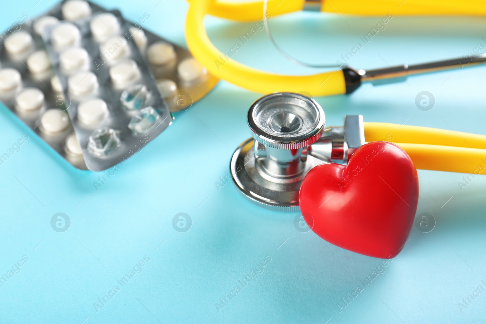 Photo of Stethoscope, small red heart and pills on table. Heart attack concept