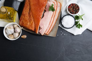 Photo of Flat lay composition with delicious smoked bacon on black table, space for text