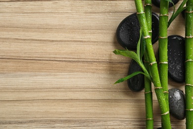 Flat lay composition with green bamboo stems on wooden background. Space for text