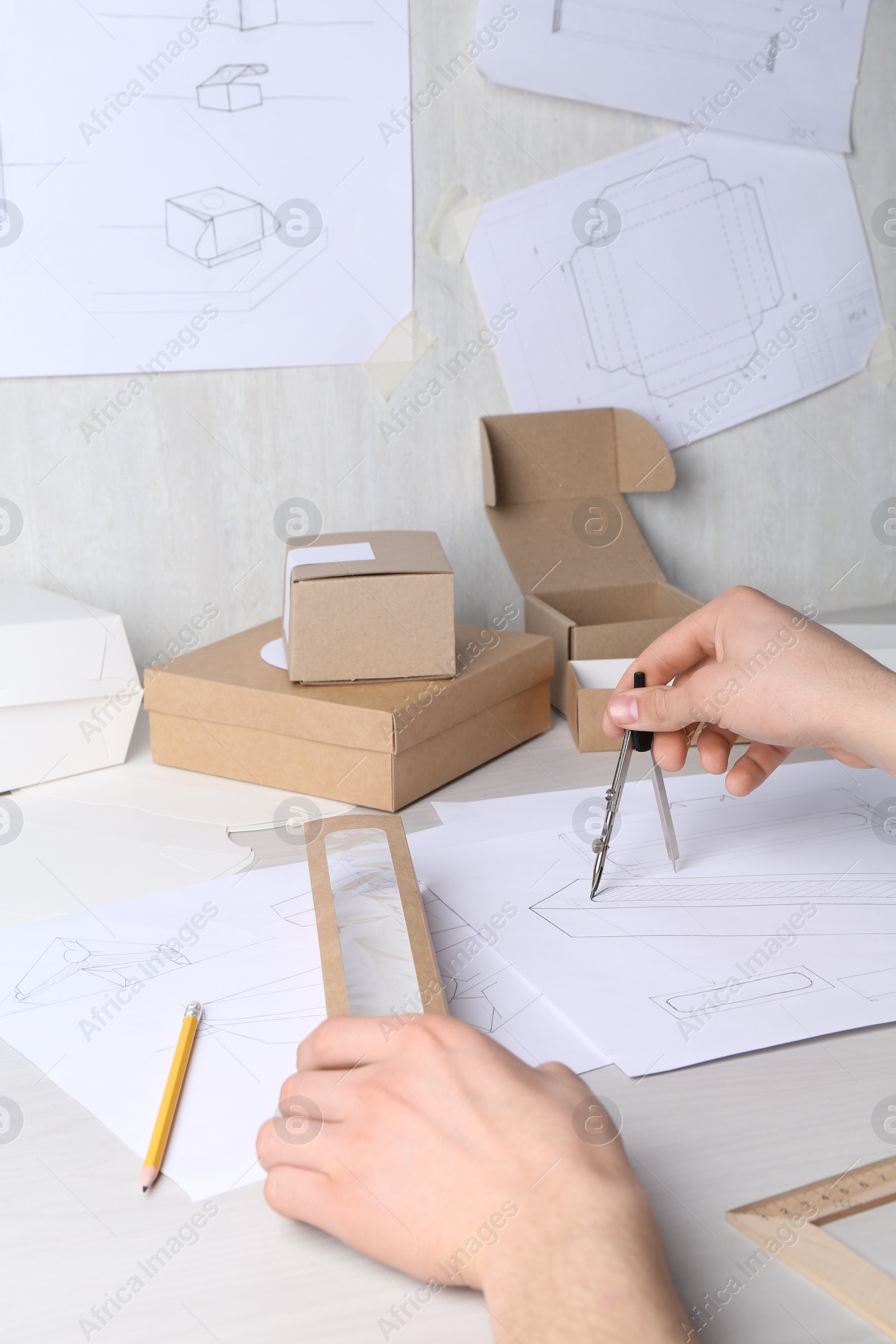 Photo of Man creating packaging design at light wooden table, closeup